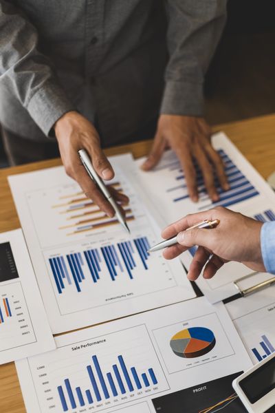Two people discussing charts and graphs on paper documents highlighting sales performance and profit
