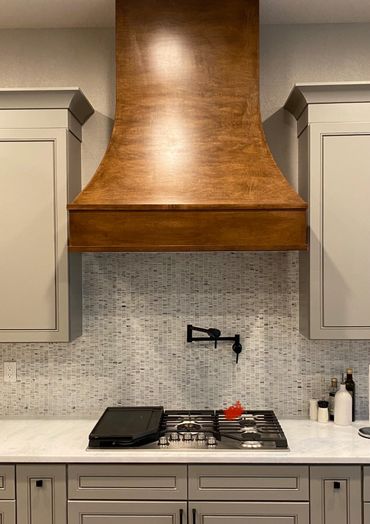 Custom kitchen remodel featuring a marble backsplash and gorgeous artisan crafted hood. 