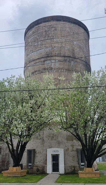Old water tower with 1923 inscription and blossoming trees in front.