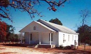 Old white church building under clear blue sky.