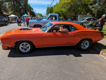 Bright orange classic muscle car with '440' decal at an outdoor car show.