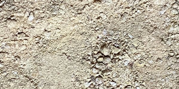 Close-up of rough, textured concrete surface with small stones.