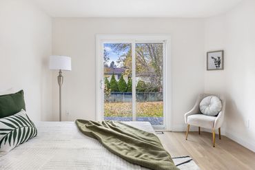 Serene bedroom with sliding glass doors, wood floors, and views of a private backyard in Uxbridge