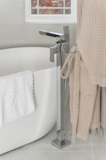 Upscale freestanding tub with modern chrome floor-mounted faucet and towel bar