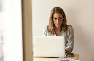 A woman sitting at a table working on her computer.