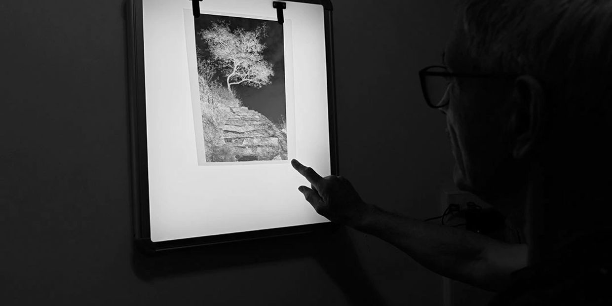 Man examining a photographic negative on a lightbox.