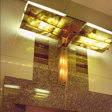 Modern ceiling light fixture with golden panels and a textured wall.
