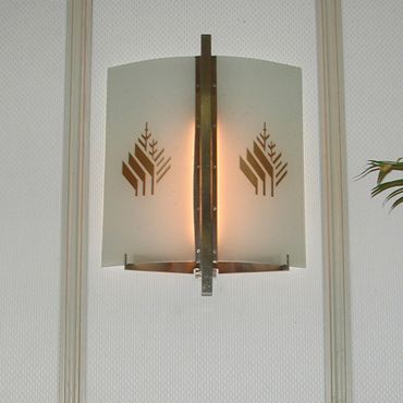 A wall-mounted light fixture with geometric tree cutouts and a warm glow.