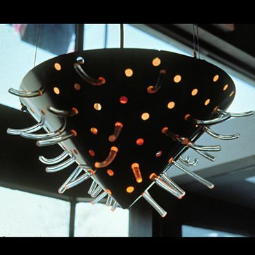 Modern pendant light with a perforated black shade and clear glass tubes.