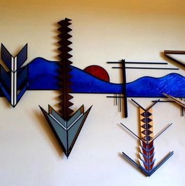 Abstract metal wall art with geometric shapes and blue mountain silhouette.