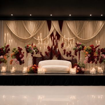 Elegant floral wedding backdrop with candles and white sofa.