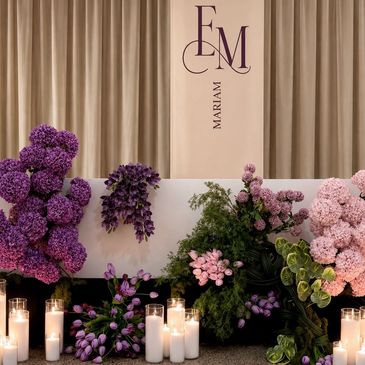 Elegant floral arrangement with candles and decorative initials.