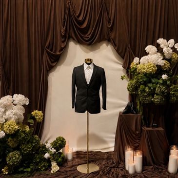 Black suit jacket on a mannequin with floral and candle decorations.