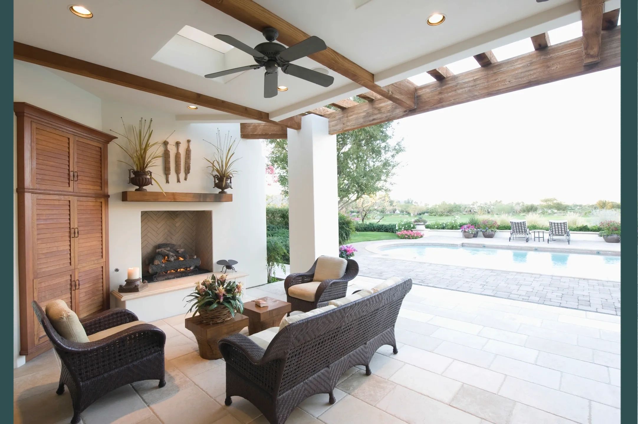 Cozy outdoor patio with fireplace and pool view.