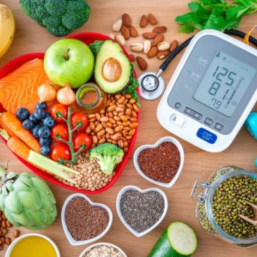 Healthy foods shaped in a heart next to a blood pressure monitor.
