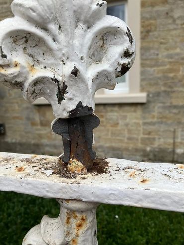 Rusty and chipped white metal fence with peeling paint.
