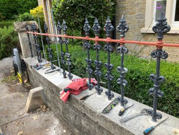 Tools and materials arranged on a stone wall next to metal fence posts being installed.