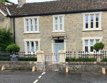 Stone house with iron railing and a small gate in front.