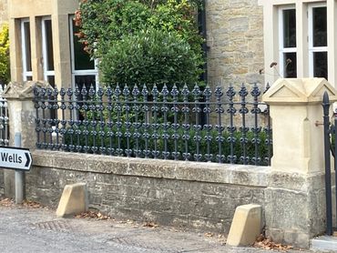 Stone house with decorative iron fence and Wells road sign.