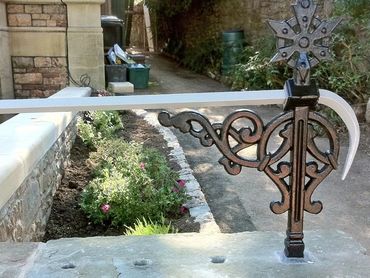 Decorative metal gate latch with intricate design on a stone wall.