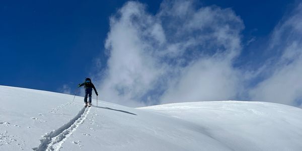 Person hiking in snowy landscape under blue sky.