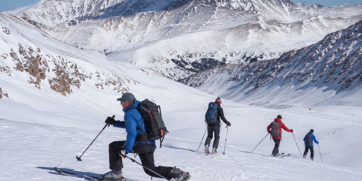 Four skiers traversing a snowy mountainous landscape.