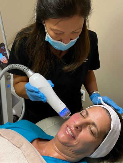 Woman receiving facial treatment with a handheld device.