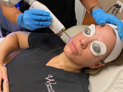 Woman receiving a laser facial treatment with protective eye gear.