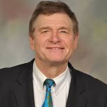 Smiling man in a suit and colorful tie.