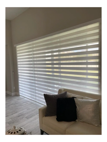 Modern living room with striped window blinds and a beige sofa with cushions.