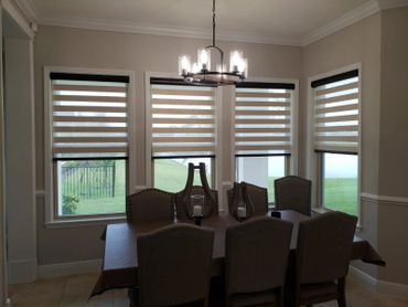 Modern dining room with striped window blinds and a chandelier.