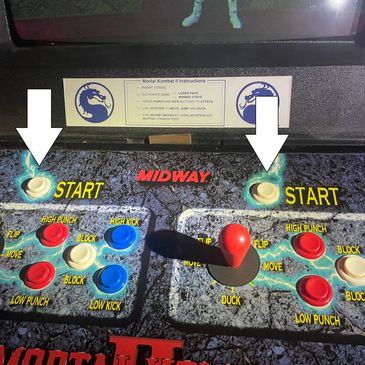 Close-up of a Mortal Kombat arcade game control panel with buttons and joystick.