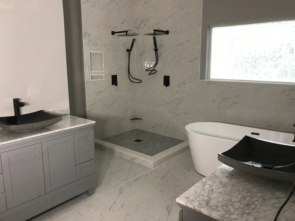 Bathroom renovation completed in Charleston, SC with a custom walk-in shower, freestanding tub, tile work, dual vanities, and modern black fixtures. Built by LG Painting + Construction. #BathroomRemodel #CharlestonSC #HomeRenovation #LGPaintingConstruction