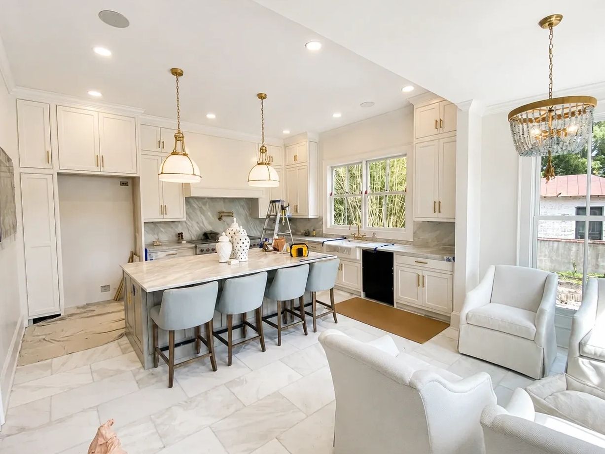 Bright and elegant white kitchen with island seating and modern lighting.