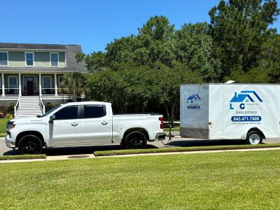 White pickup truck towing a white trailer in front of a house.