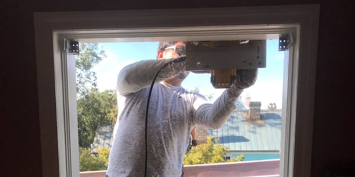Carpenter repairing a wood window frame with a power tool
