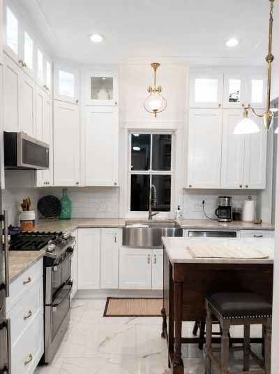 Modern kitchen with white cabinets and marble floor.