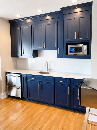 Modern kitchen with navy blue cabinets and stainless steel appliances.