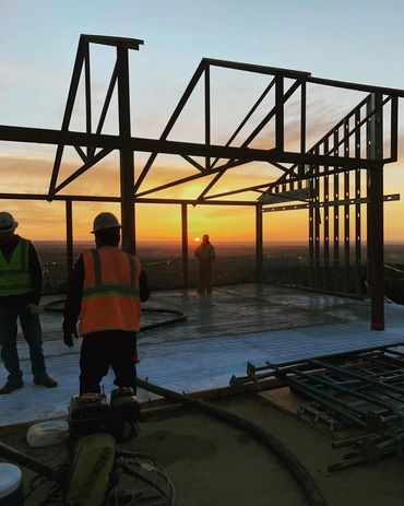 Construction workers at a building site during sunset.