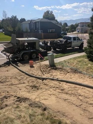 A pickup truck towing a trailer with equipment on a residential street.