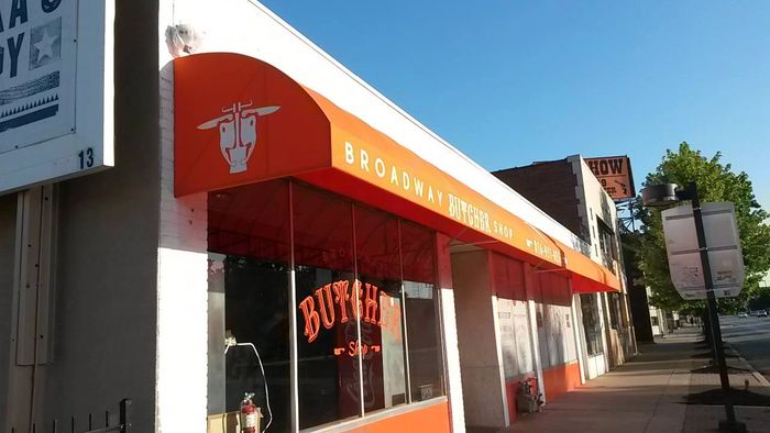 Picture of the outside of the shop from the street including glass windows and an orange awning