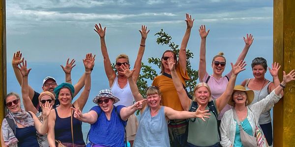 Group of women joyfully raising hands outdoors.