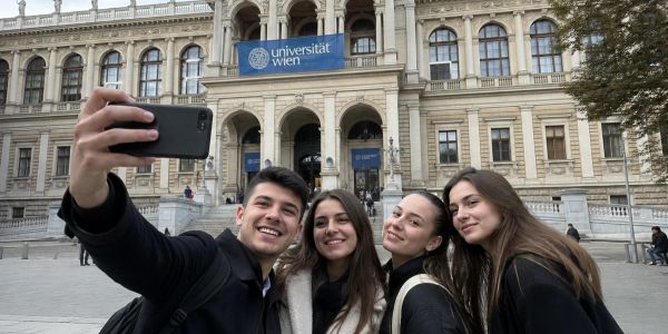 Four friends taking a selfie outside Universität Wien.