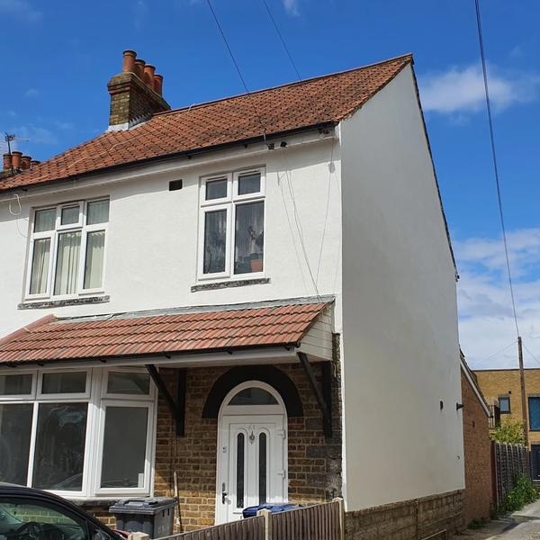 White two-story house with red tiled roof on a sunny day.