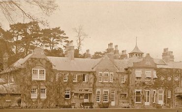 Sepia photo of Castle Malwood, a large historic estate with ivy-covered walls.