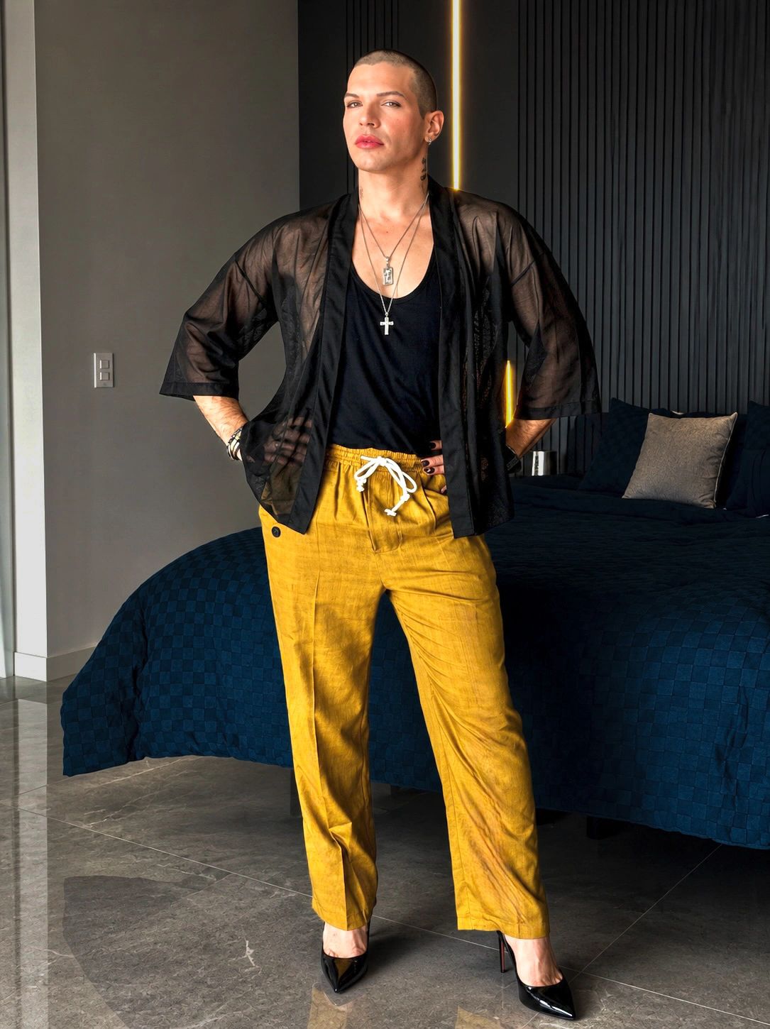 Person posing indoors in stylish outfit with yellow pants.