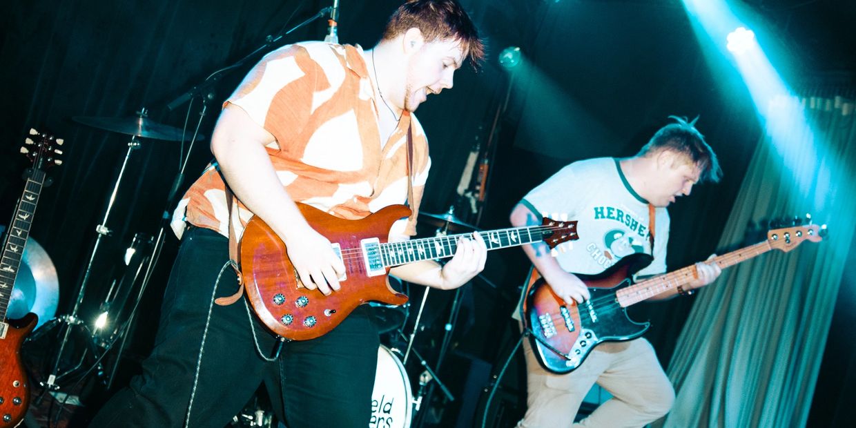 Two musicians passionately playing guitar and bass on stage.
