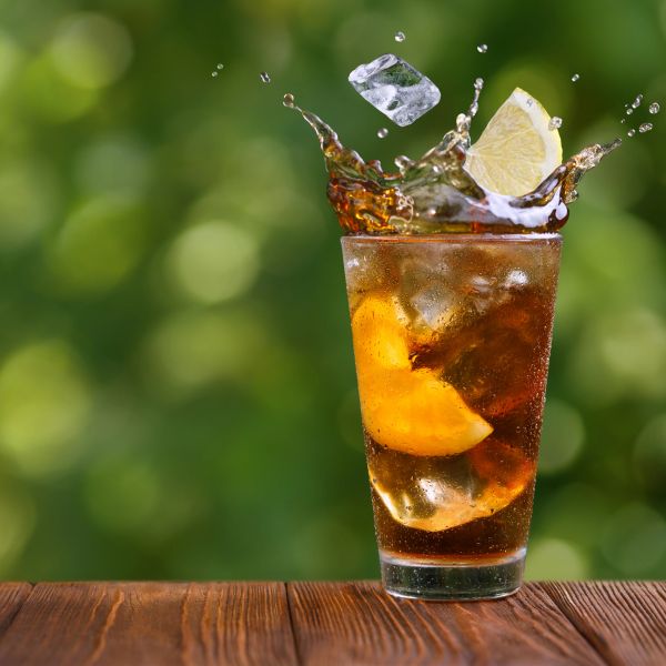 Refreshing iced tea with lemon splash in a clear glass.