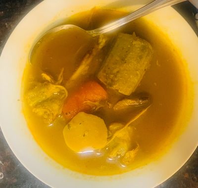 A bowl of hearty soup with vegetables and meat.