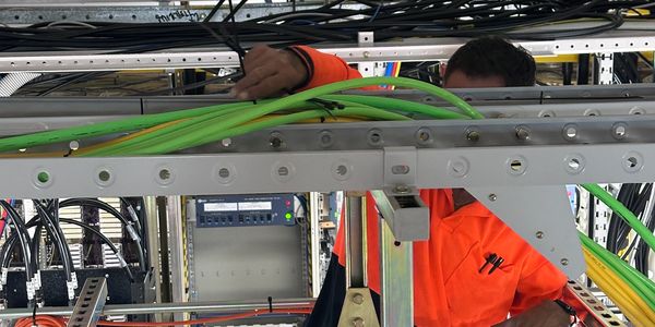Technician working on network cables in data center rack.